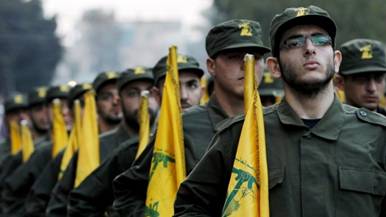 Hezbollah fighters hold party flags during a parade in a southern suburb of Beirut, Lebanon. (photo credit: AP/Hussein Malla/File)